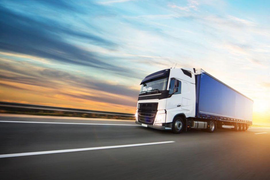 Loaded European truck on motorway in beautiful sunset light. On the road transportation and cargo.